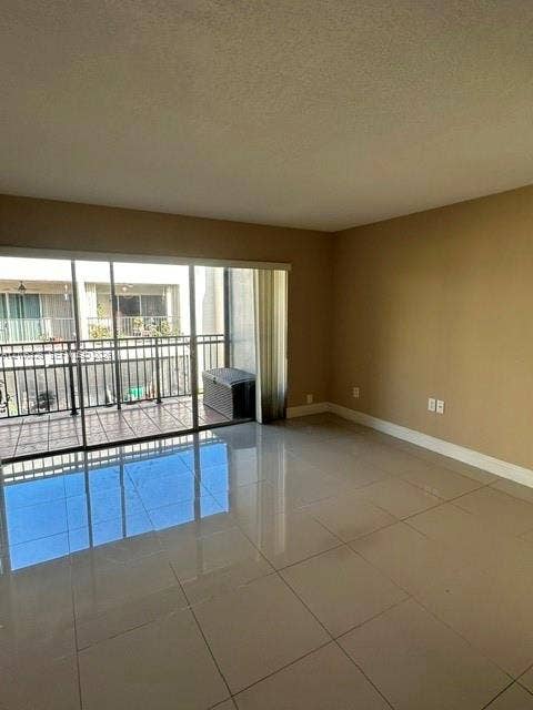 220 NW 87th Avenue, #K212, Miami, Miami, FL 33172 Large-format tile flooring, neutral wall tones, and floor-to-ceiling sliding glass doors opening to an exterior balcony with metal railing