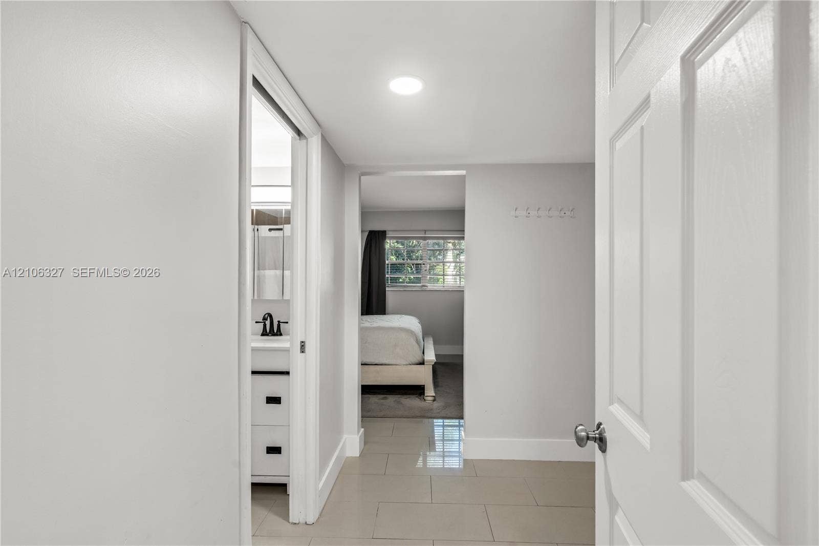 Hallway featuring large-format tile flooring, recessed lighting, and a white six-panel door