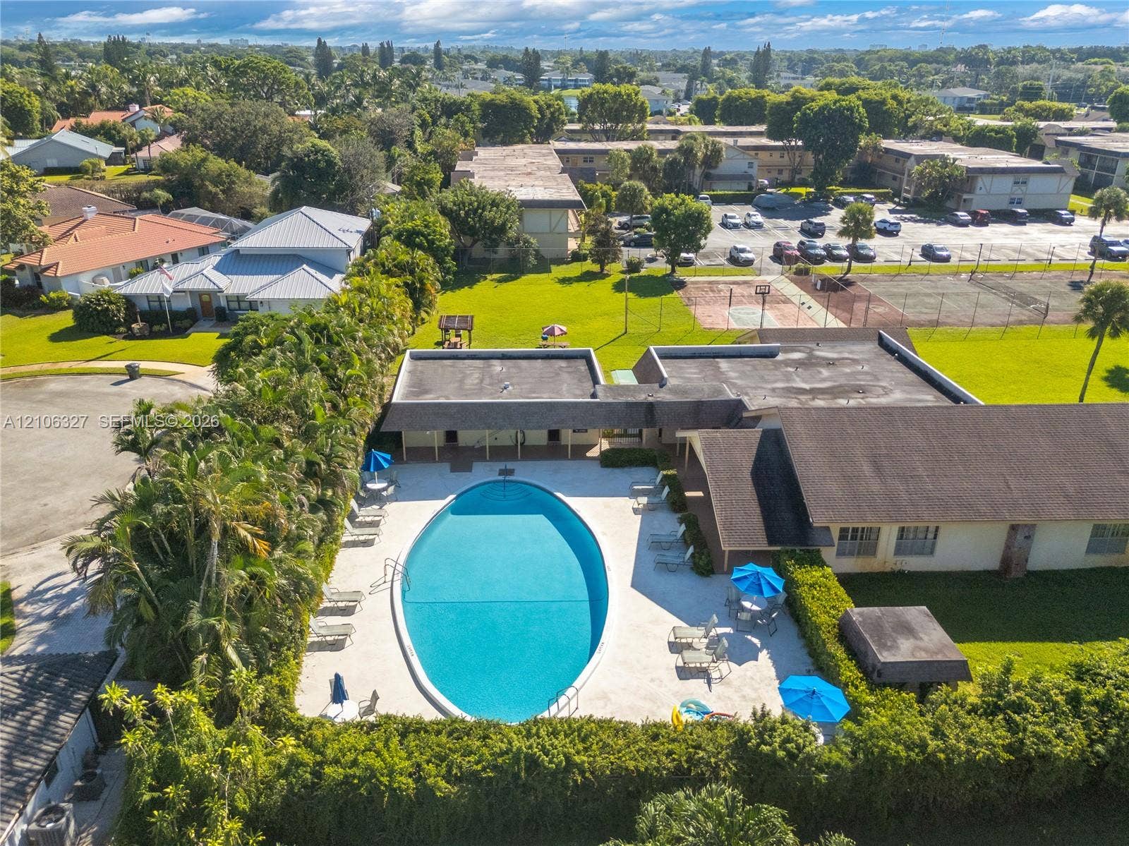 Oval-shaped swimming pool with a concrete pool deck, surrounded by manicured landscaping and mature trees
