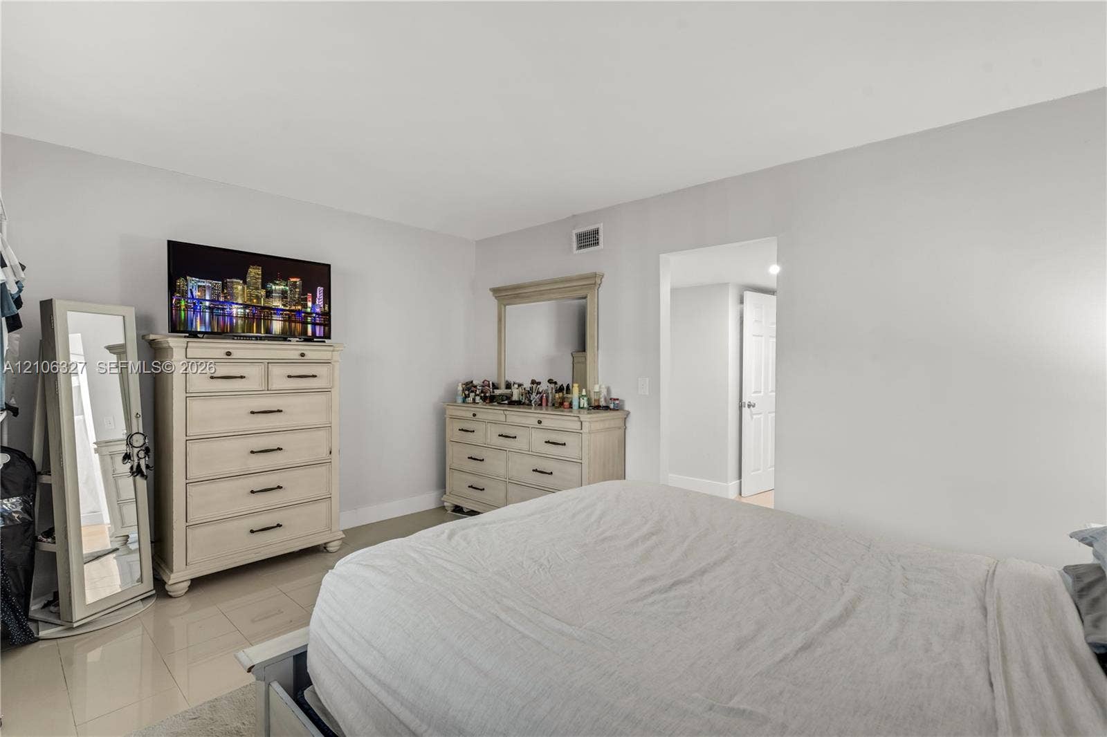 Spacious room featuring neutral wall paint, large-format tile flooring, and a six-panel interior door