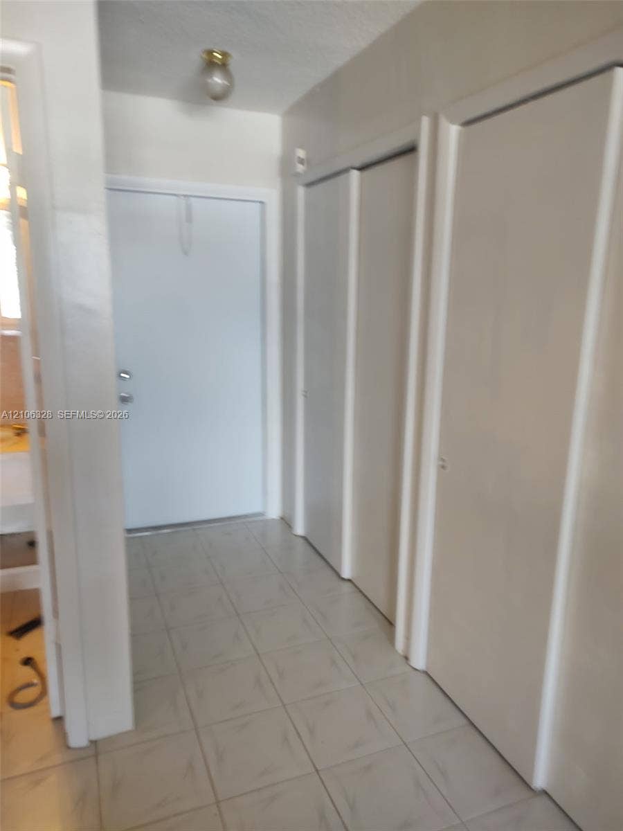 Entryway featuring light-toned tile flooring, dual-panel closet doors, and flush-mount lighting