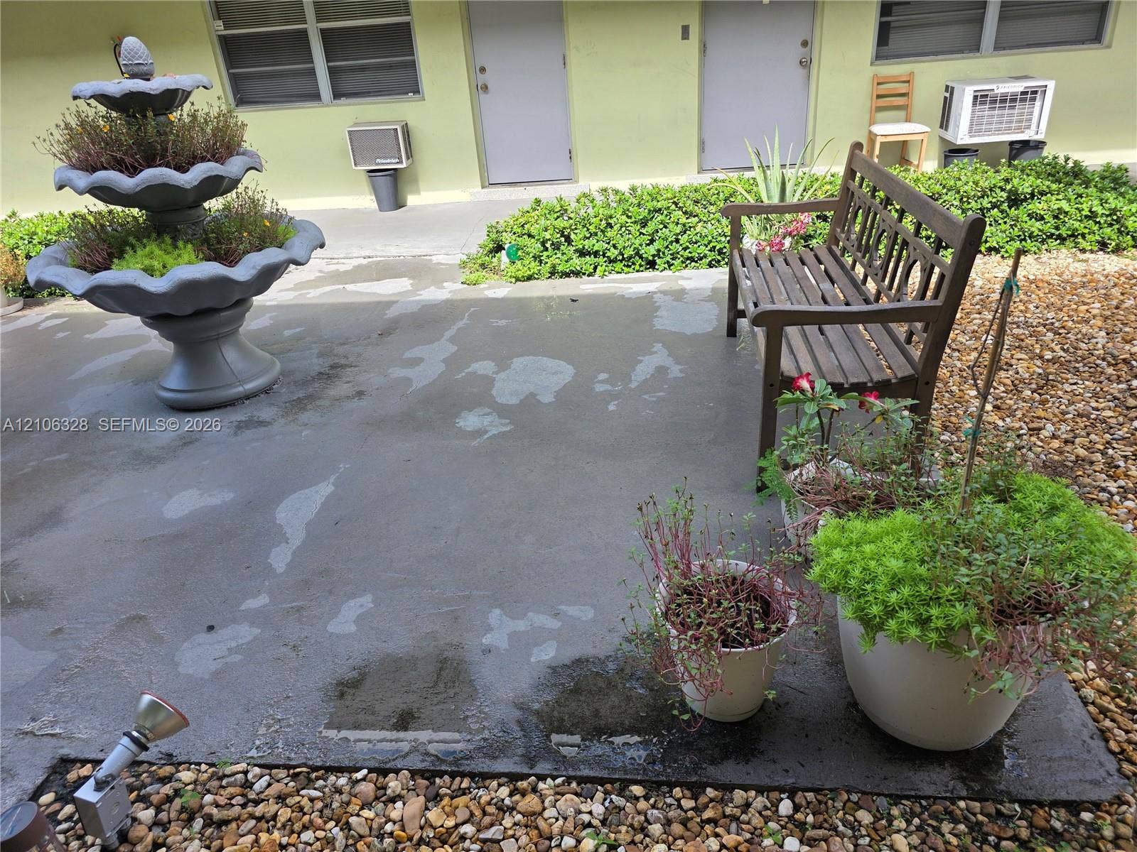 Concrete patio featuring a multi-tiered fountain and rock garden landscaping