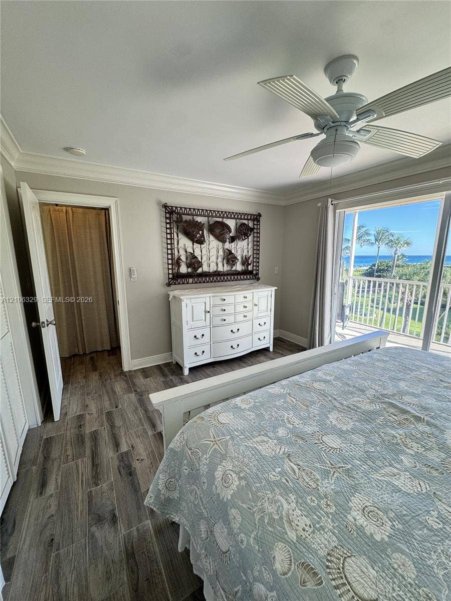 3600 N Ocean Drive, #423, Riviera Beach, Riviera Beach, FL 33404 Wood-finish flooring, ceiling fan with integrated light, crown molding, and sliding glass doors opening to a balcony with an ocean backdrop