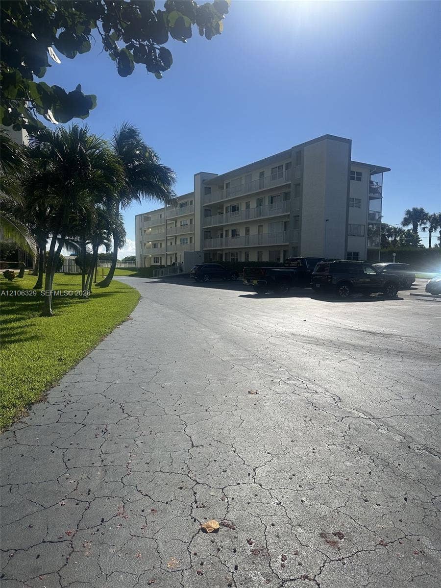 3600 N Ocean Drive, #423, Riviera Beach, Riviera Beach, FL 33404 Multi-story residential building featuring covered balconies, asphalt parking area, and manicured green space with mature palms