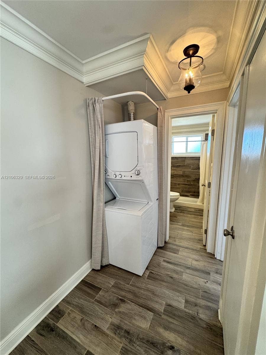 3600 N Ocean Drive, #423, Riviera Beach, Riviera Beach, FL 33404 Laundry area featuring stacked laundry appliances, recessed ceiling crown molding, wood-finish flooring, and a decorative pendant light fixture