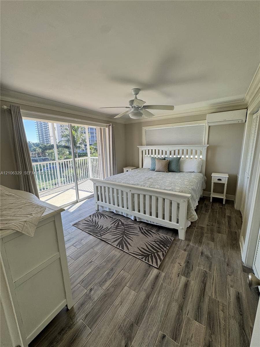 3600 N Ocean Drive, #423, Riviera Beach, Riviera Beach, FL 33404 Wood-finish tile flooring, ceiling fan, crown molding, wall-mounted air conditioning unit, and sliding glass doors with balcony access