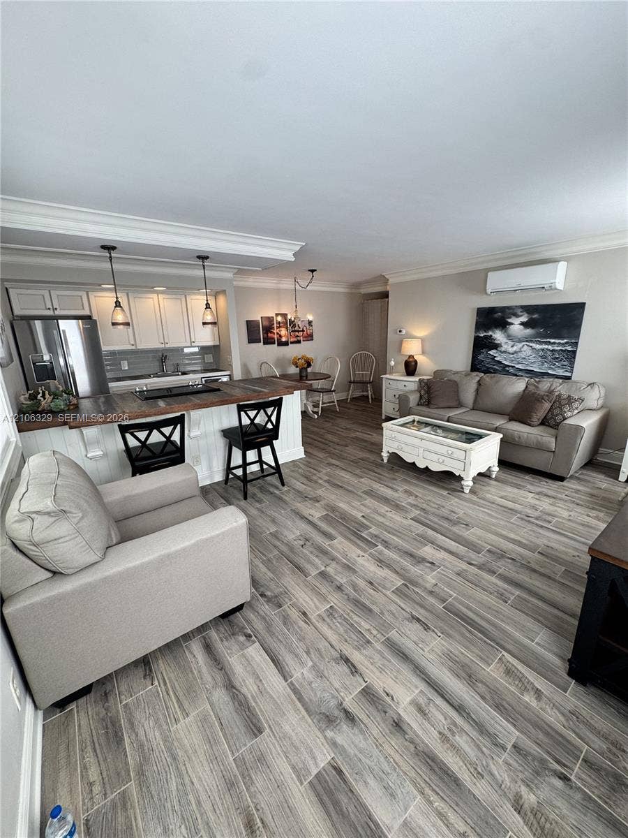 3600 N Ocean Drive, #423, Riviera Beach, Riviera Beach, FL 33404 Open-concept area featuring wood-finish tile flooring, white cabinetry with crown molding, a breakfast bar with a wood countertop, and dual pendant lighting