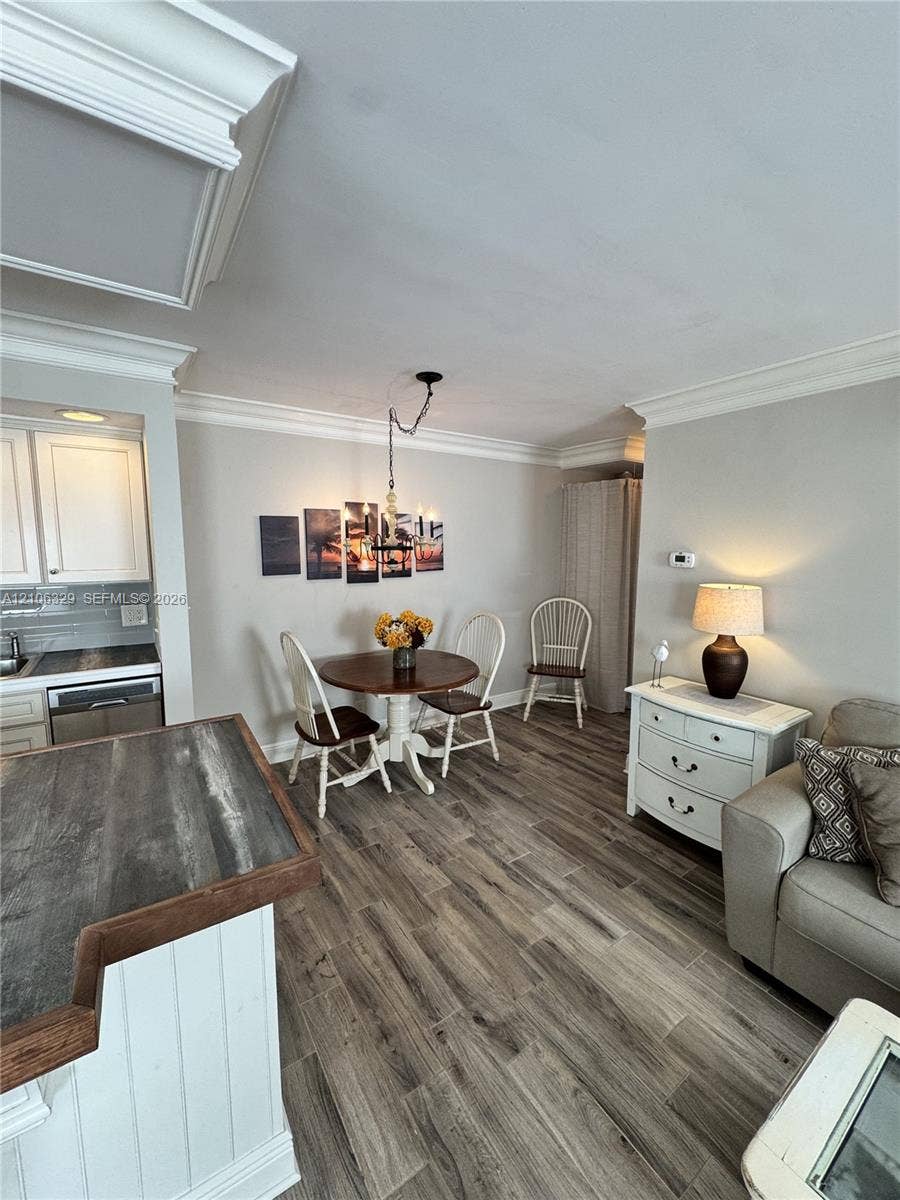 3600 N Ocean Drive, #423, Riviera Beach, Riviera Beach, FL 33404 Wood-finish flooring, crown molding, and an elevated kitchen counter featuring a wood-tone surface and vertical paneling