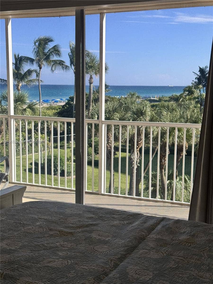 3600 N Ocean Drive, #423, Riviera Beach, Riviera Beach, FL 33404 Screened balcony featuring vertical white railing and coastal scenery including palm trees and ocean