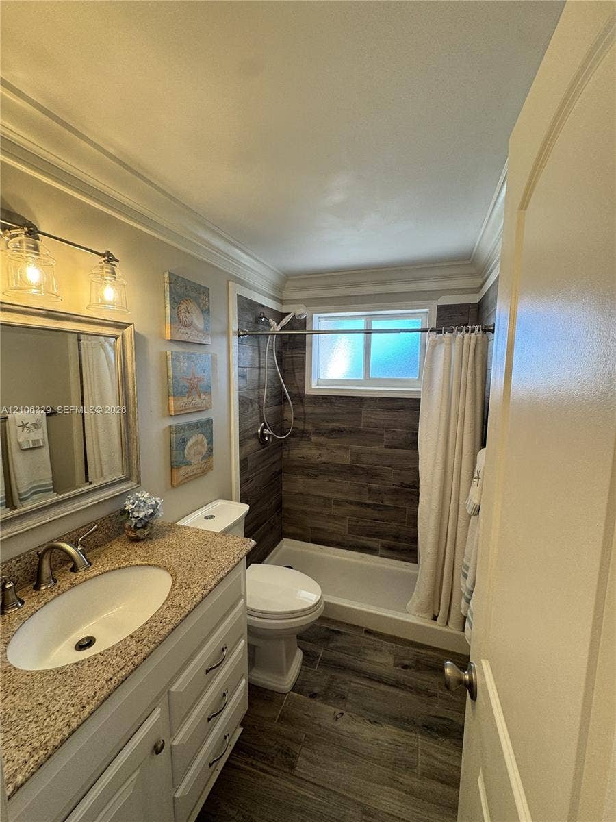 3600 N Ocean Drive, #423, Riviera Beach, Riviera Beach, FL 33404 Bathroom featuring a stone-composite countertop, white vanity cabinetry, wood-finish flooring, and wood-finish tile shower surround