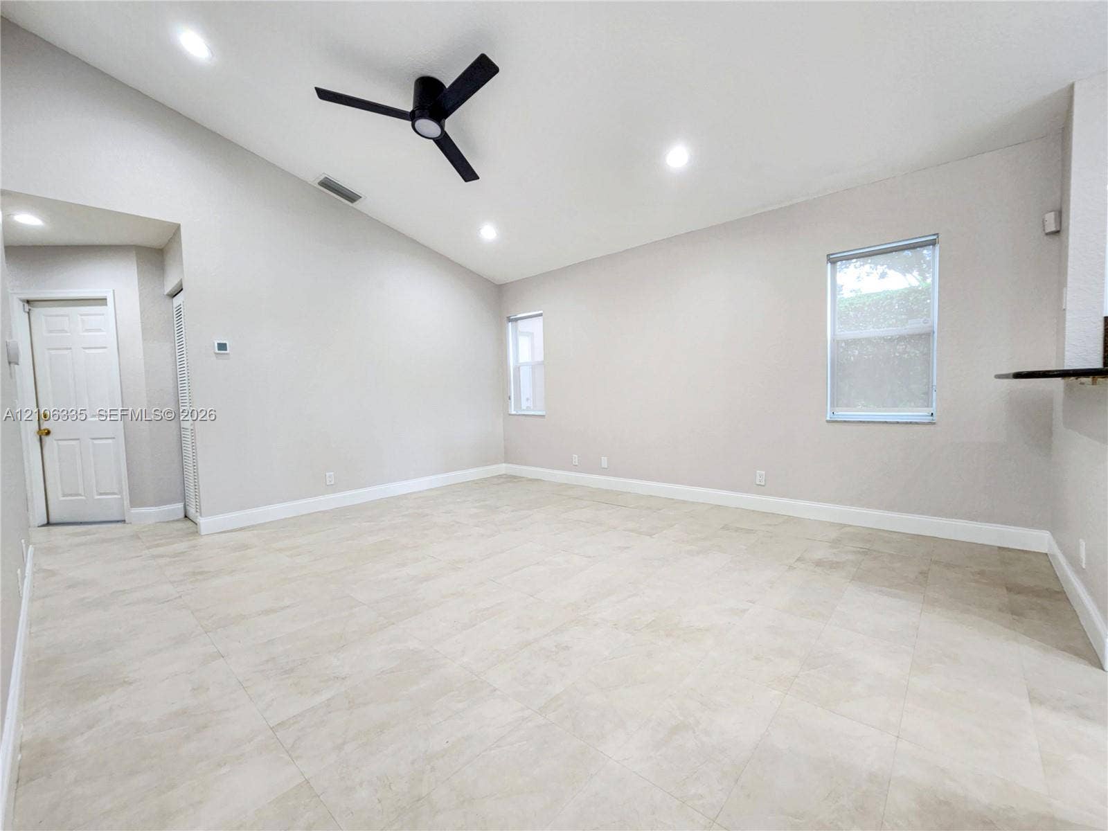 Vaulted ceilings, neutral tile flooring, recessed lighting, matte black ceiling fan, and multi-pane windows