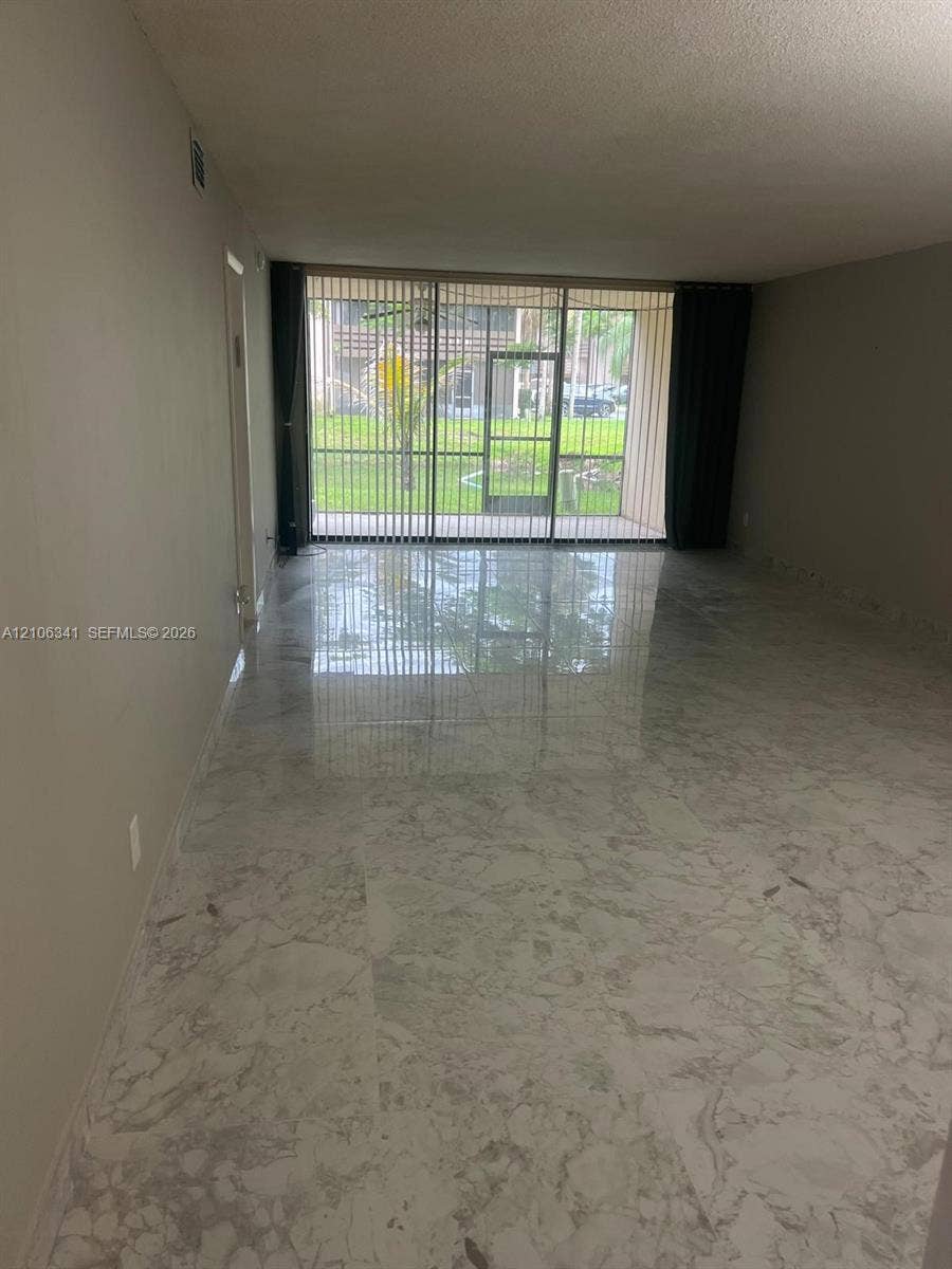 Polished stone-finish tile flooring throughout with full-height sliding glass doors leading to a screened enclosure