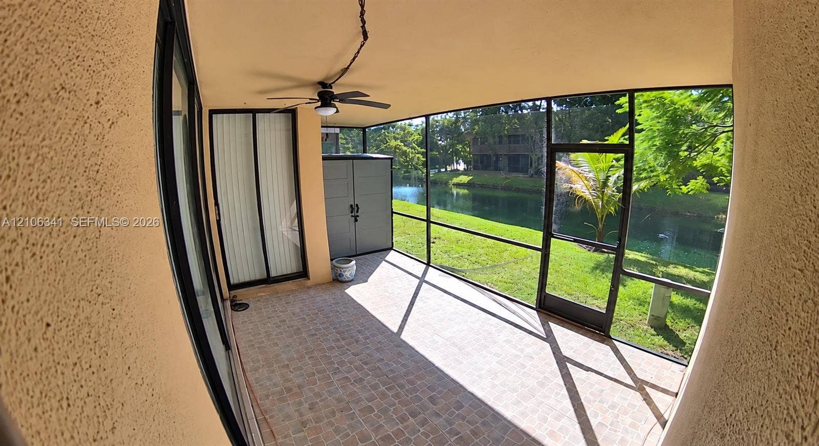 Screened-in lanai featuring tiled flooring, a ceiling fan, and sliding glass door entry