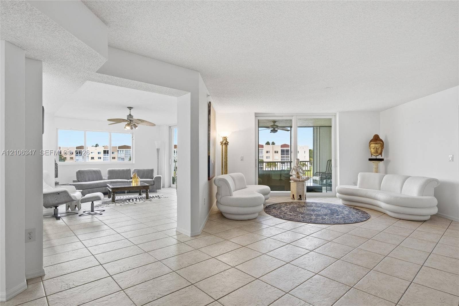 7759 Granville Drive, #306, Tamarac, FL 33321 Open-concept interior featuring large-format ceramic tile flooring, multiple ceiling fans, and expansive sliding glass doors providing outdoor access