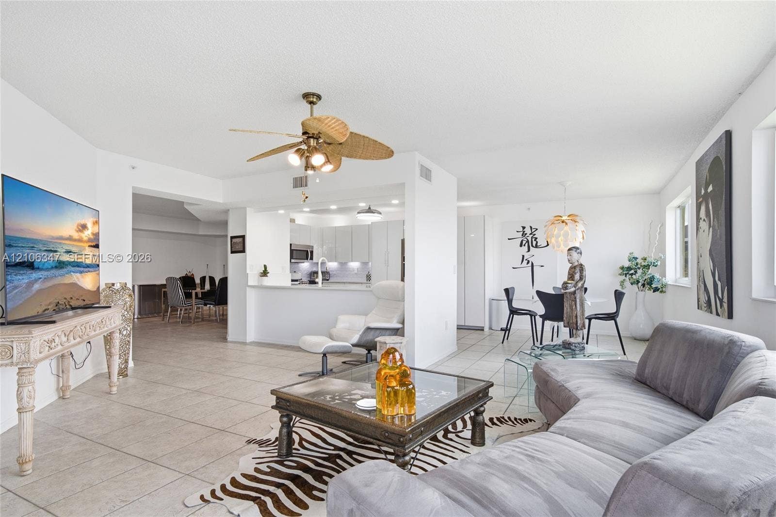 7759 Granville Drive, #306, Tamarac, FL 33321 Open-concept interior featuring large-format ceramic tile flooring, a kitchen breakfast bar, and a ceiling fan with woven-style blades