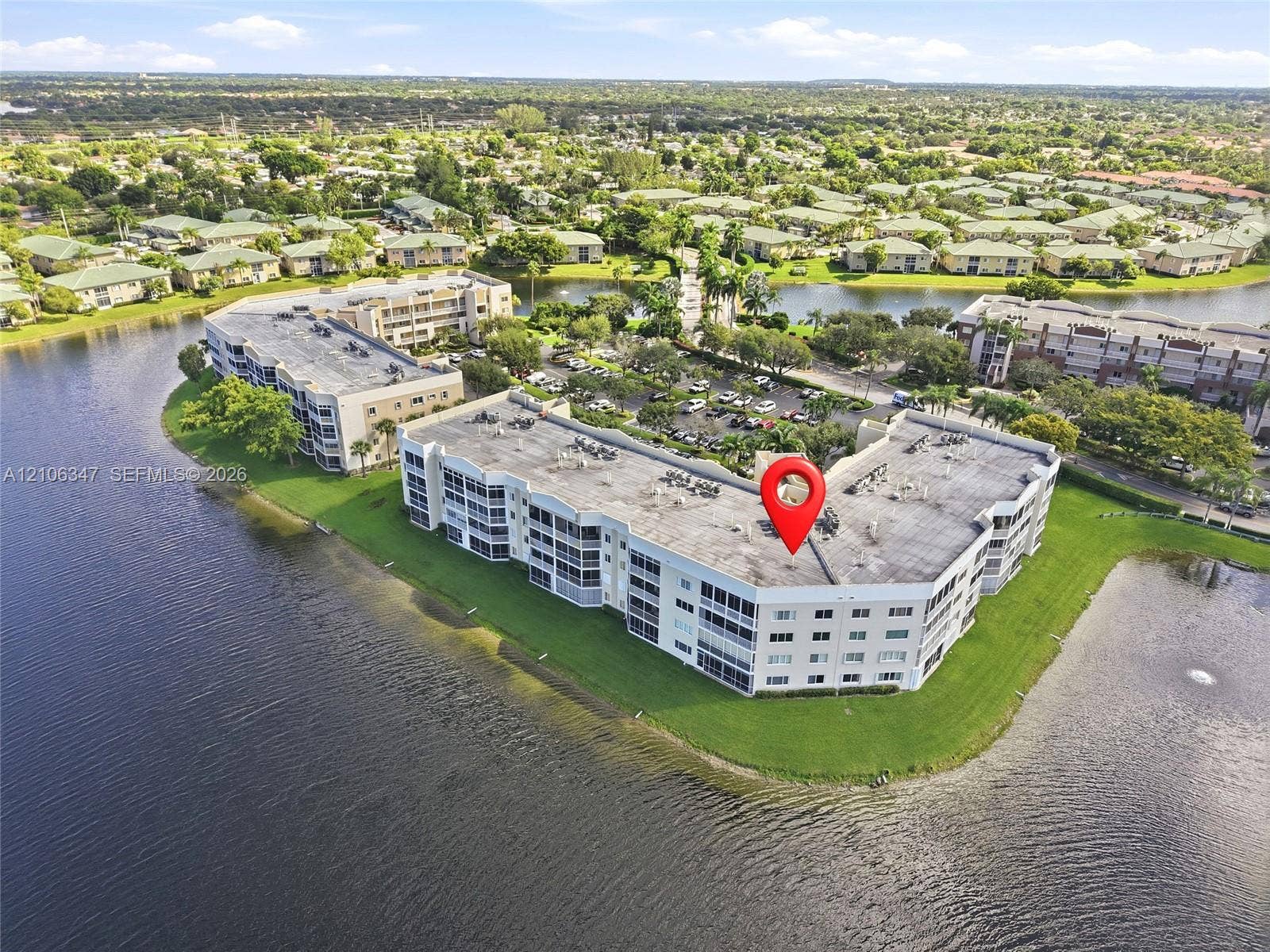 7759 Granville Drive, #306, Tamarac, FL 33321 Multi-story residential building situated on a waterfront lot featuring manicured landscaping and perimeter walking areas