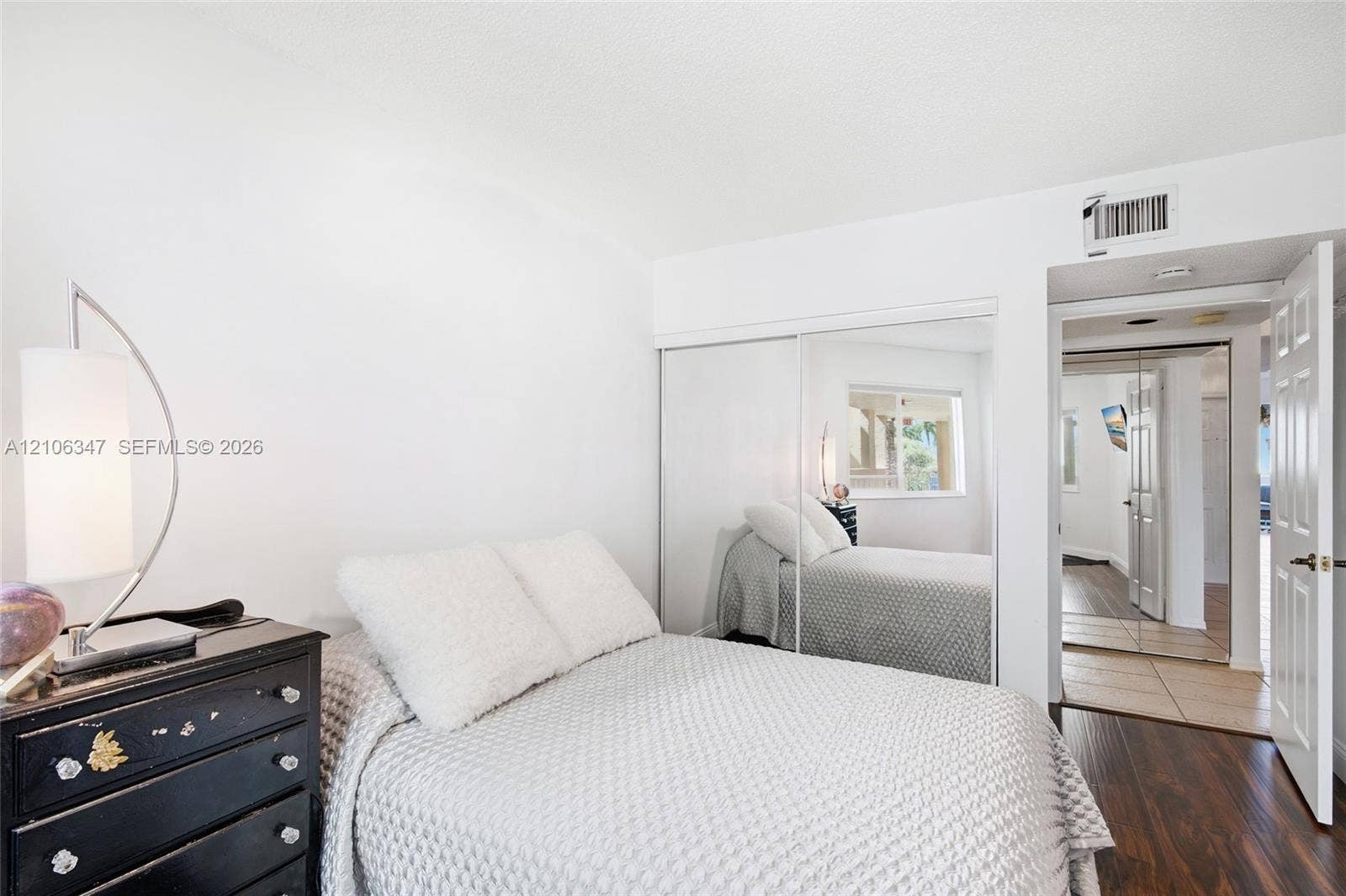 7759 Granville Drive, #306, Tamarac, FL 33321 Room featuring wood-finish flooring, sliding mirror-panel closet doors, and a six-panel interior door