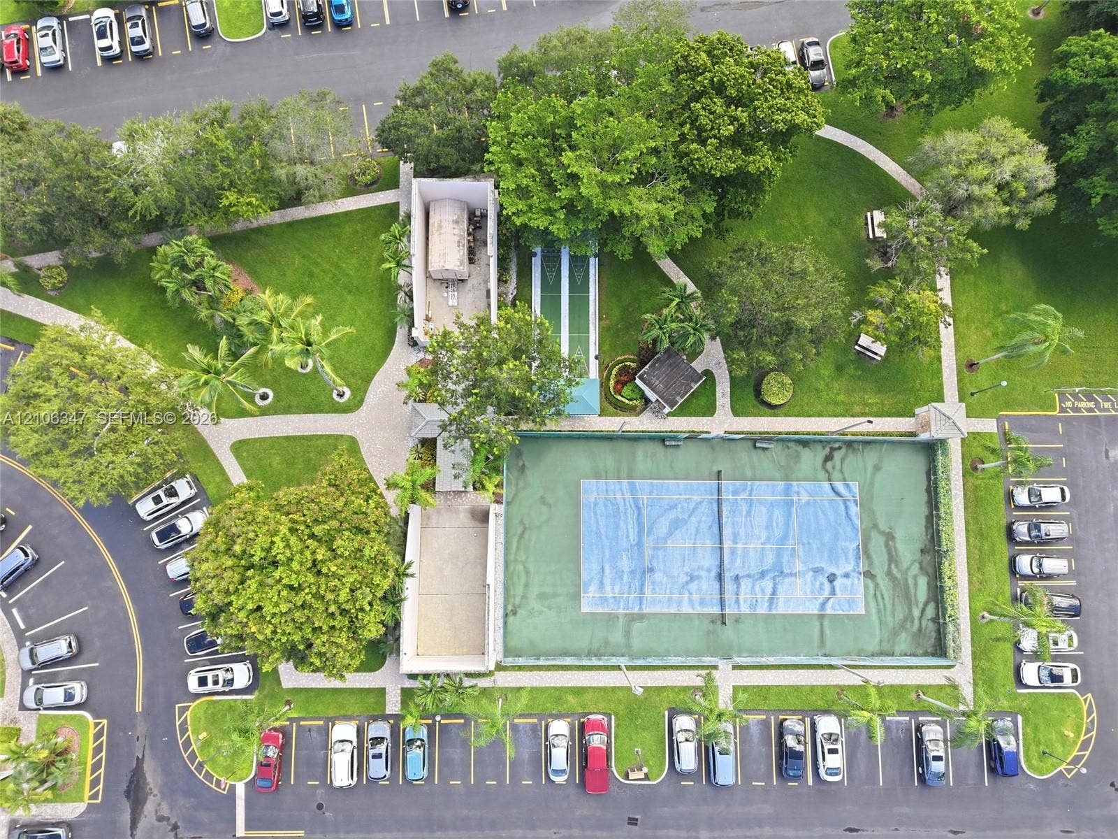 7759 Granville Drive, #306, Tamarac, FL 33321 Aerial perspective of recreational grounds featuring a fenced tennis court, shuffleboard court, paved walkways, and extensive landscaped green space