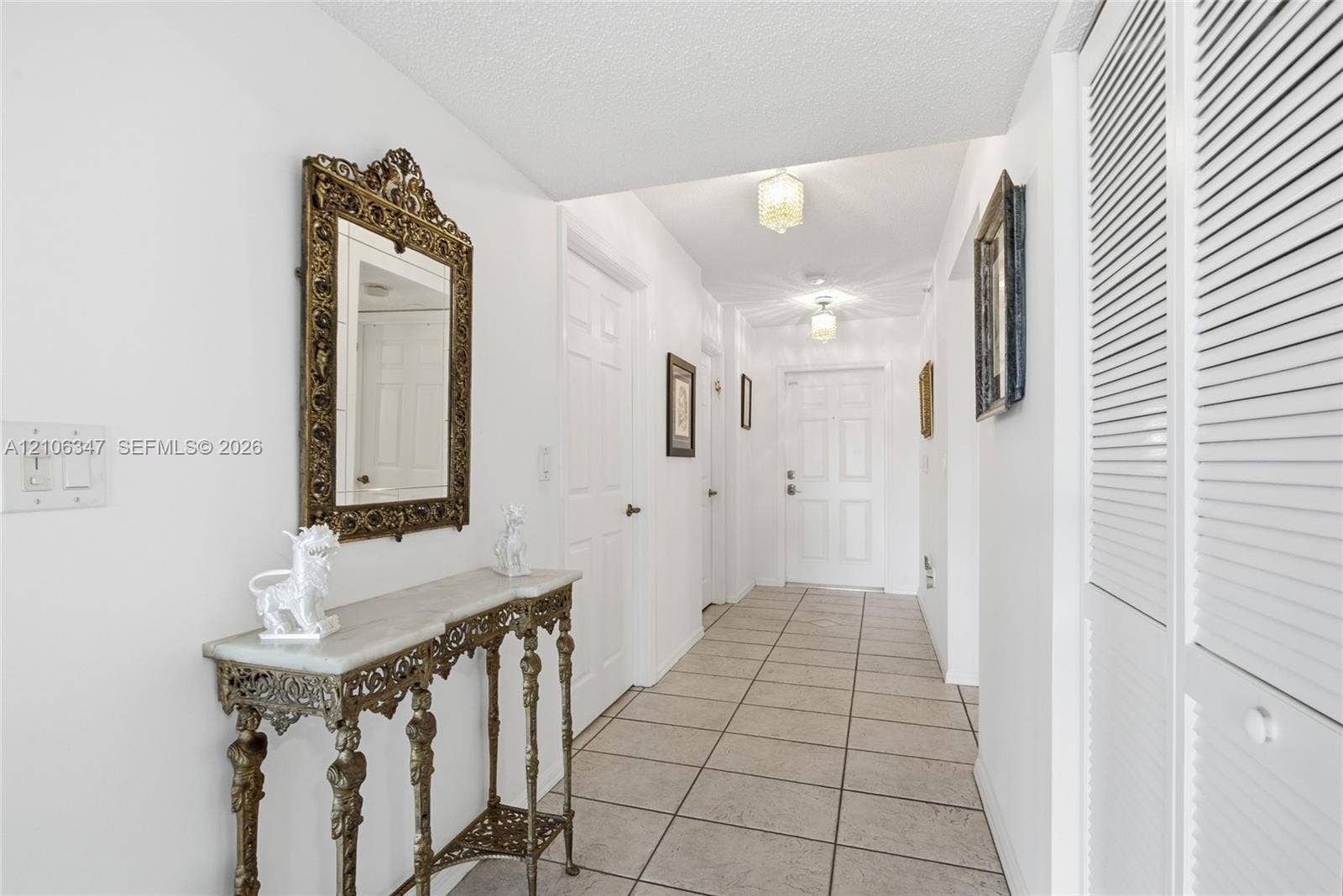 7759 Granville Drive, #306, Tamarac, FL 33321 Entryway featuring neutral tile flooring, multi-panel doors, ceiling-mounted light fixtures, and white louvered closet doors