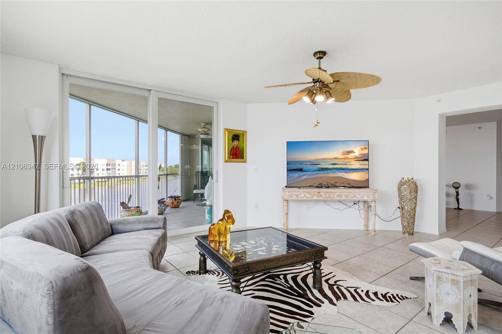 7759 Granville Drive, #306, Tamarac, FL 33321 Living area featuring large-format ceramic tile flooring, floor-to-ceiling sliding glass doors, and a ceiling fan with integrated lighting