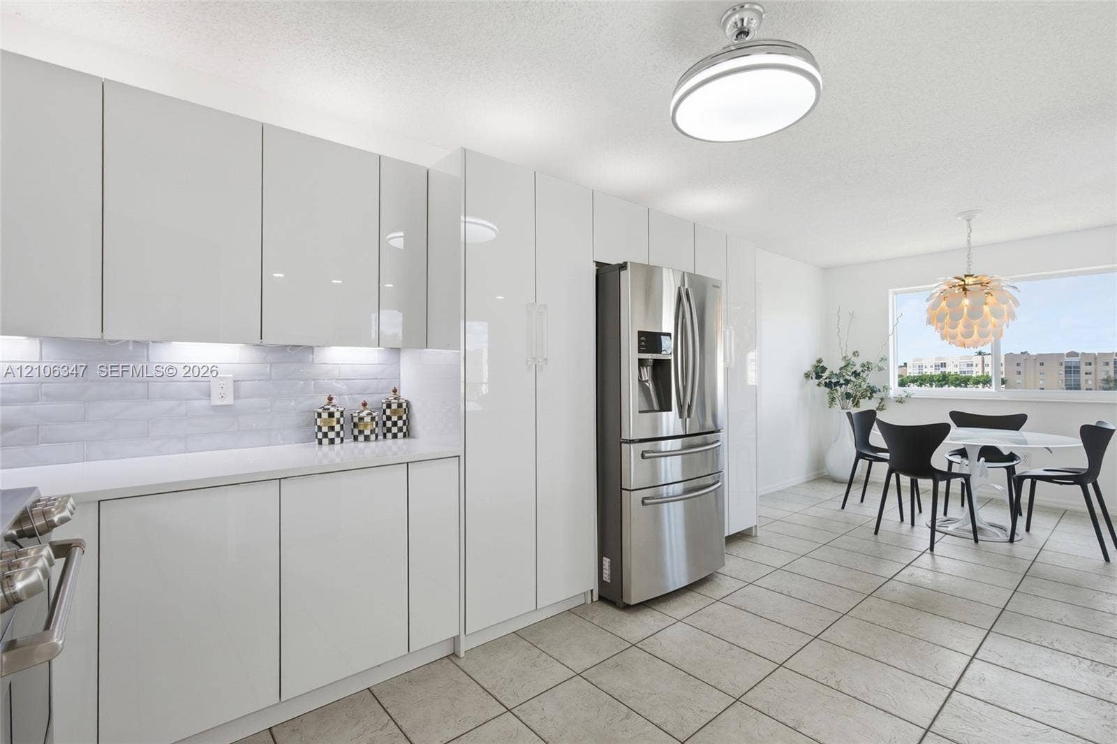 7759 Granville Drive, #306, Tamarac, FL 33321 High-gloss white cabinetry, white solid-surface countertops, horizontal tile backsplash, stainless steel french-door refrigerator, and ceramic tile flooring