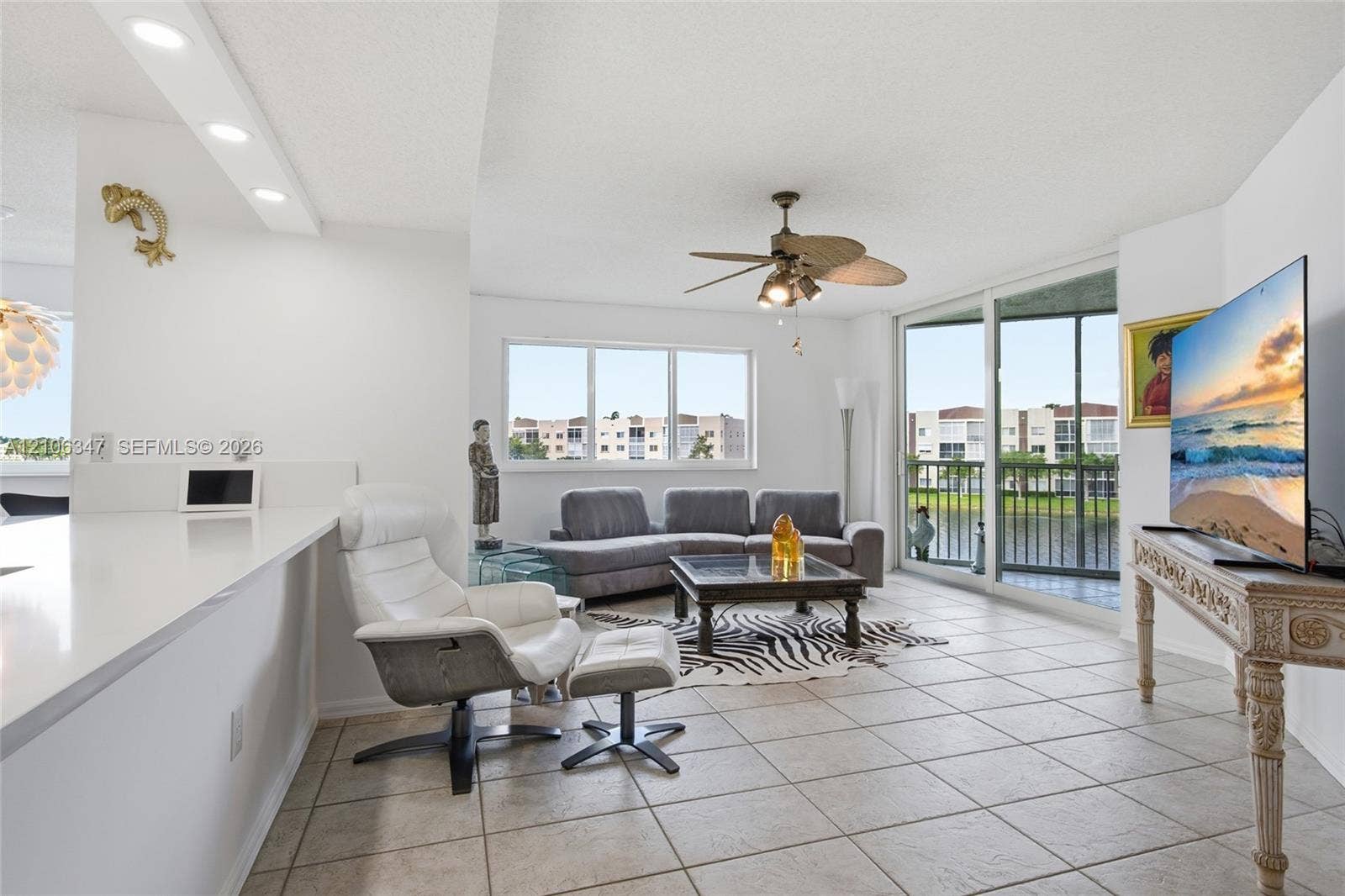 7759 Granville Drive, #306, Tamarac, FL 33321 Living area featuring neutral tile flooring, recessed lighting, a ceiling fan with integrated lighting, and sliding glass doors leading to a balcony