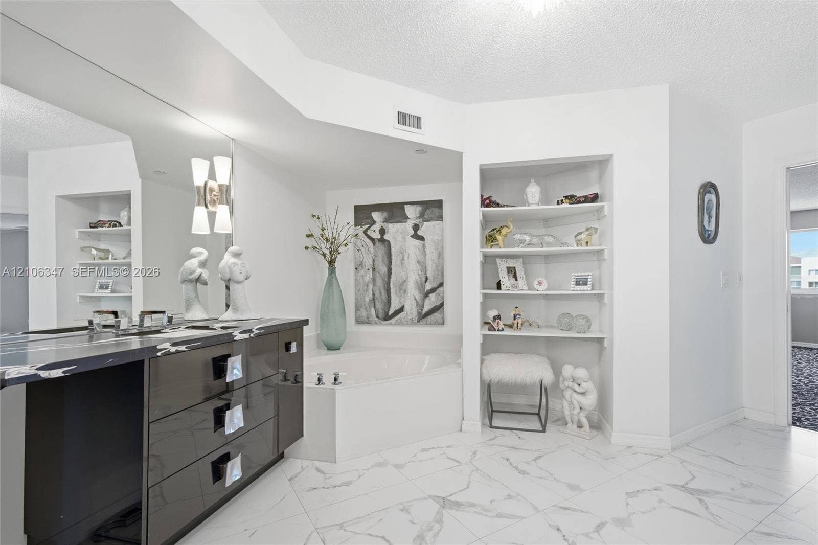 7759 Granville Drive, #306, Tamarac, FL 33321 Bathroom featuring large-format tile flooring, a deep soaking tub, high-gloss cabinetry, a sprawling wall mirror, and built-in corner shelving