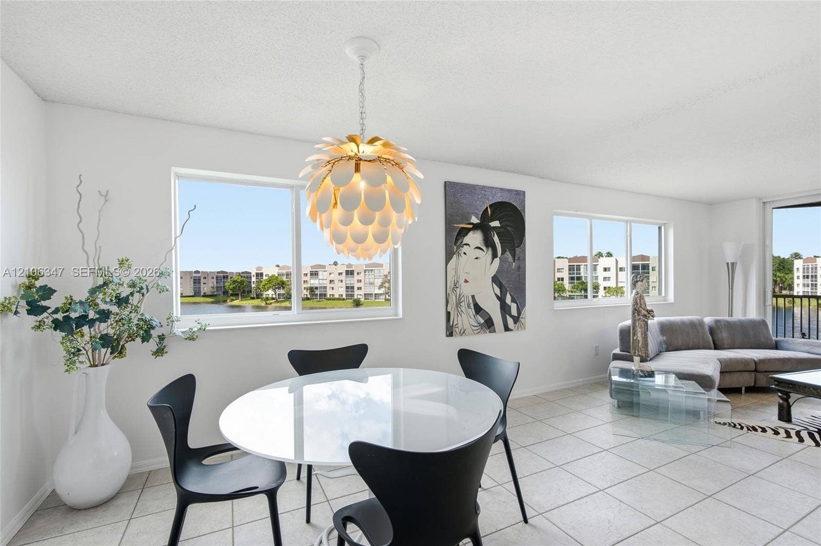 7759 Granville Drive, #306, Tamarac, FL 33321 Open-concept interior featuring large-format ceramic tile flooring, multiple windows providing natural light, and a decorative petal-style pendant light fixture