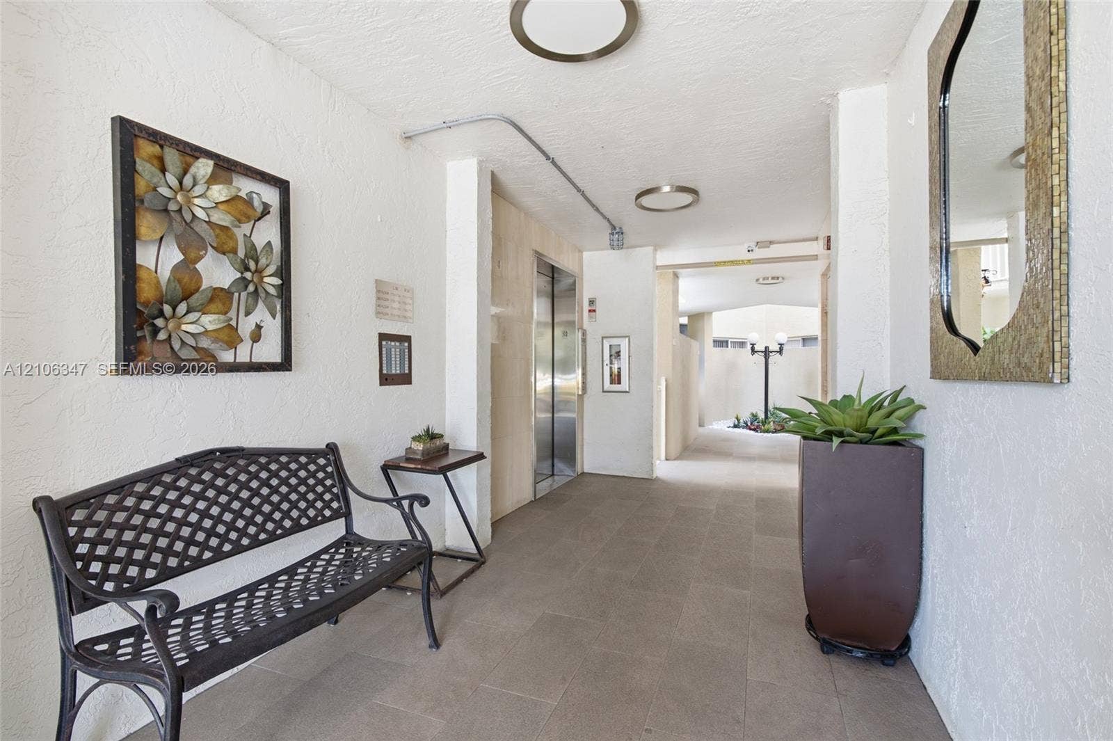 7759 Granville Drive, #306, Tamarac, FL 33321 Neutral-toned stone flooring, elevator access with metallic doors, and flush-mount circular ceiling lighting