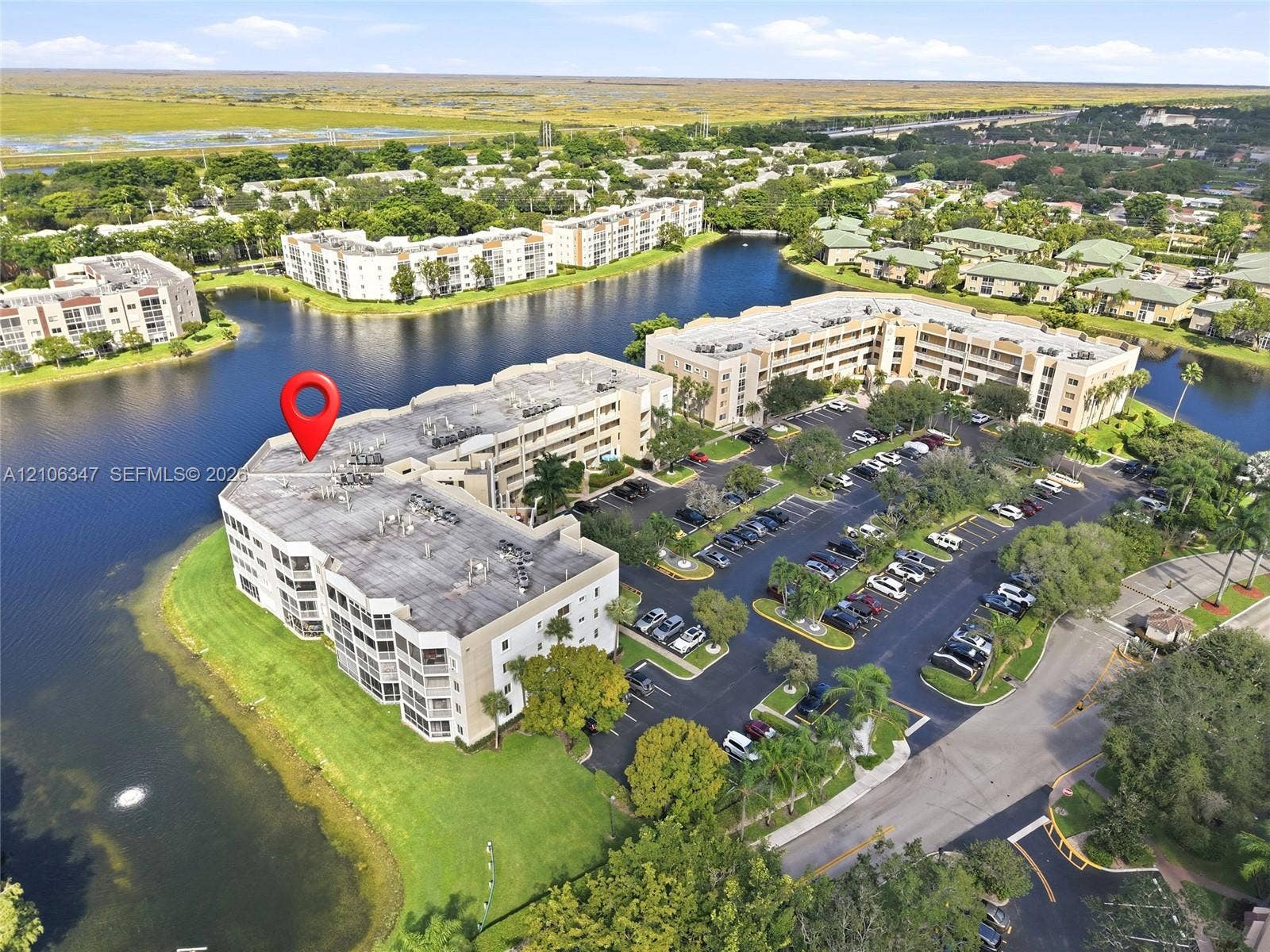 7759 Granville Drive, #306, Tamarac, FL 33321 Multi-story residential building situated on a waterfront lot featuring surface parking and mature landscaping