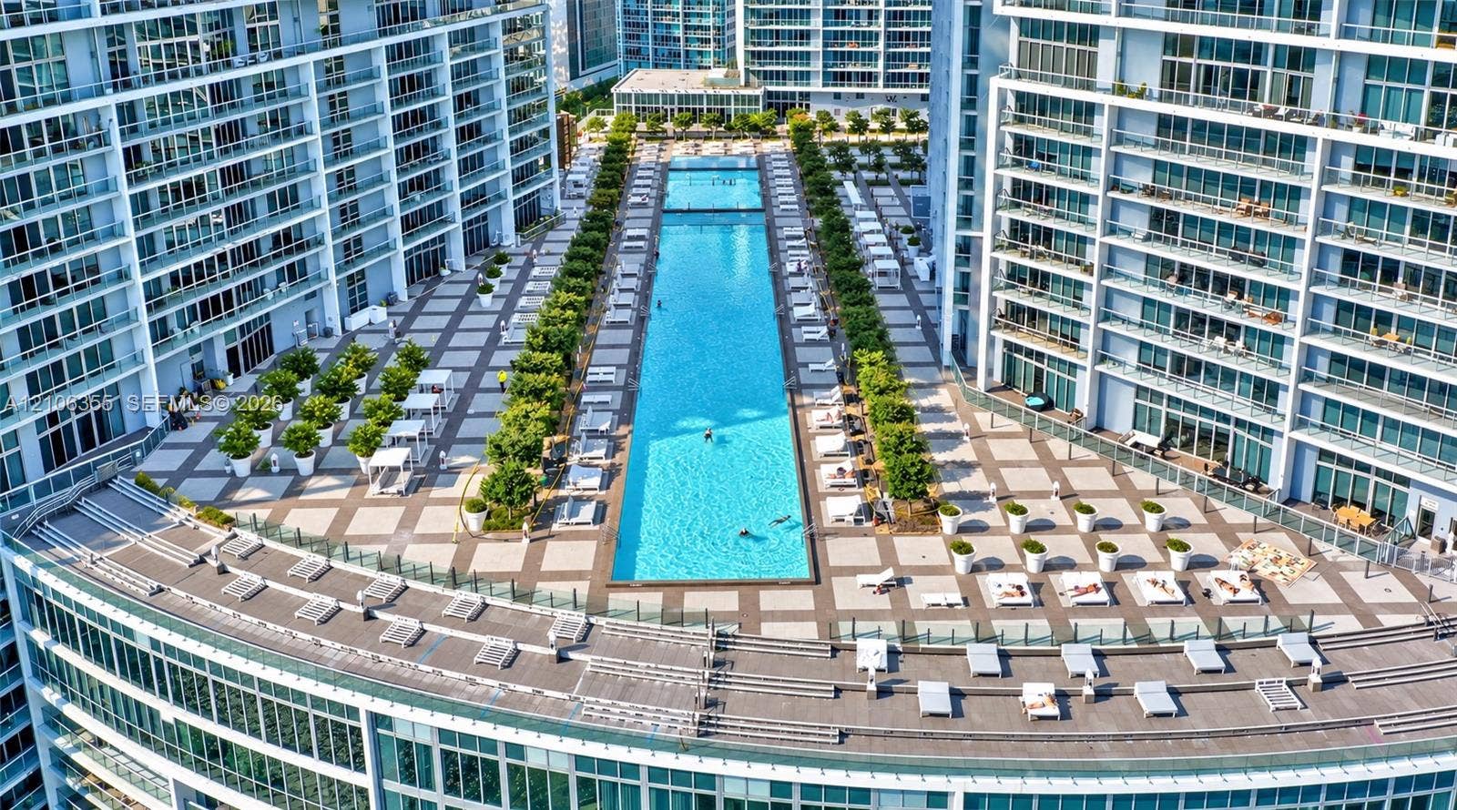495 Brickell Avenue, #1906, Miami, Miami, FL 33131 Expansive elevated terrace featuring a linear swimming pool, tiled hardscaping, manicured landscaping, and glass balcony railings