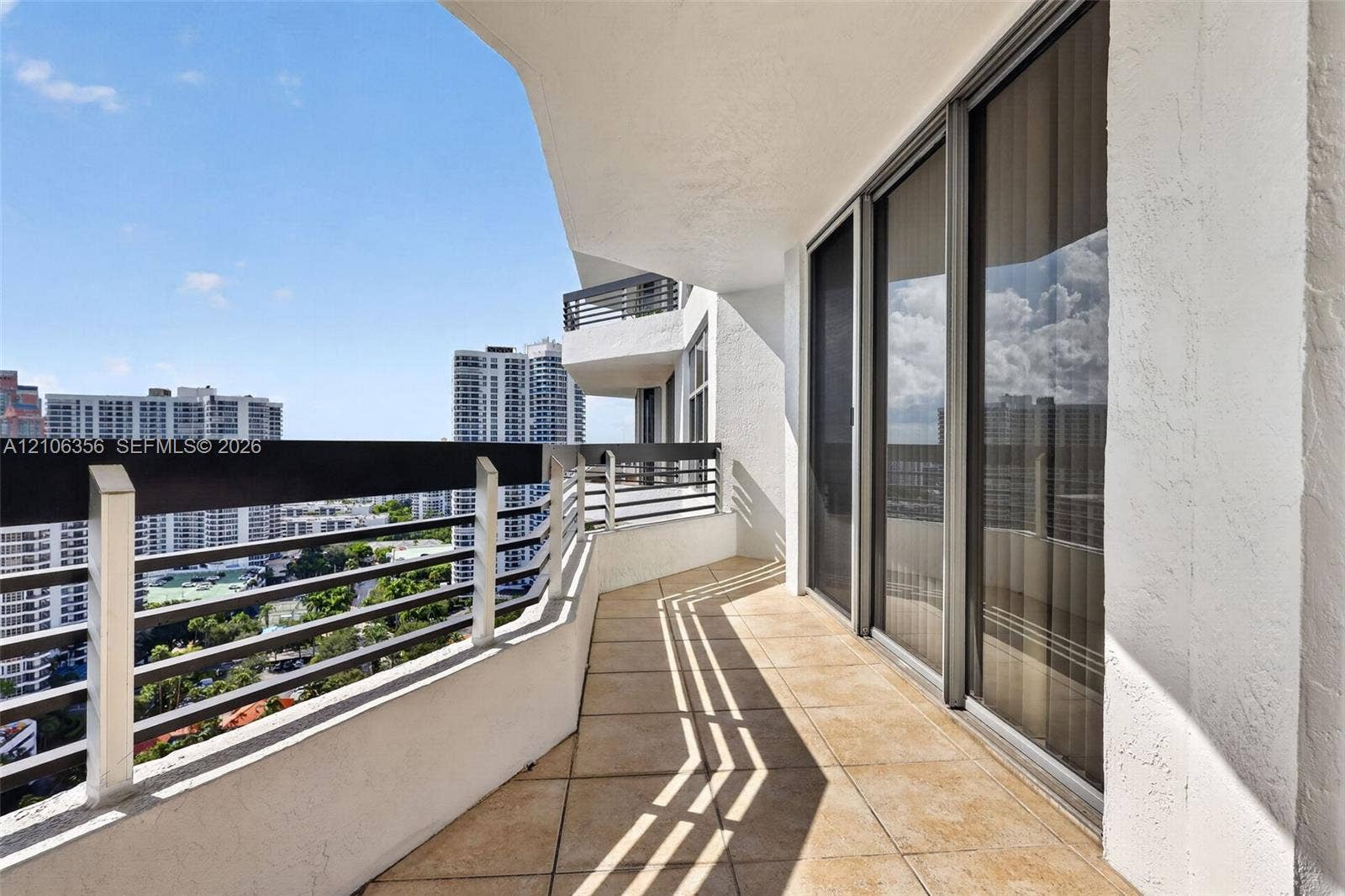 Covered balcony featuring tile flooring, metal railings, and floor-to-ceiling glass sliding doors