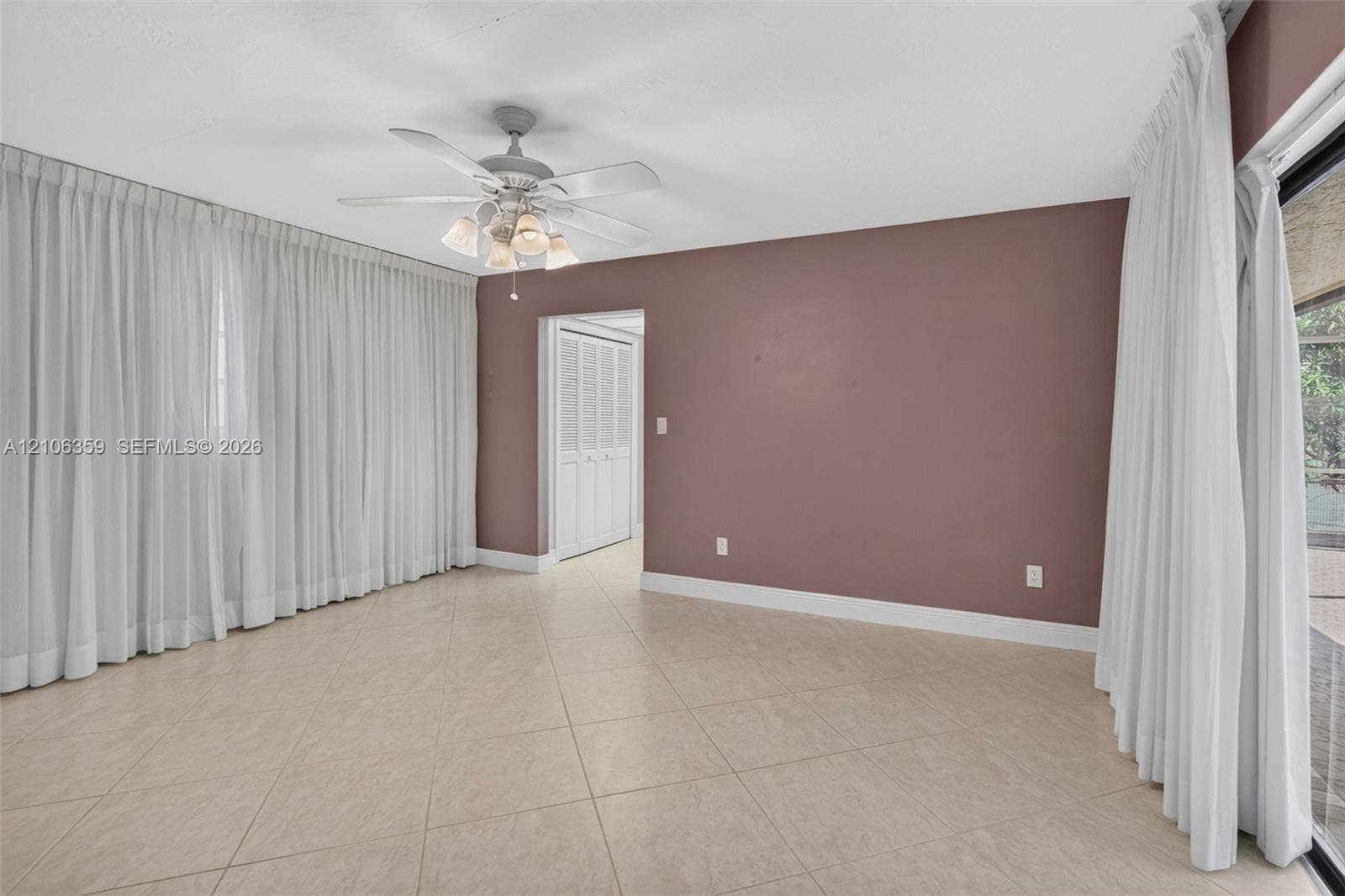 Interior space featuring tile flooring, ceiling fan with integrated lighting, and louvered closet doors