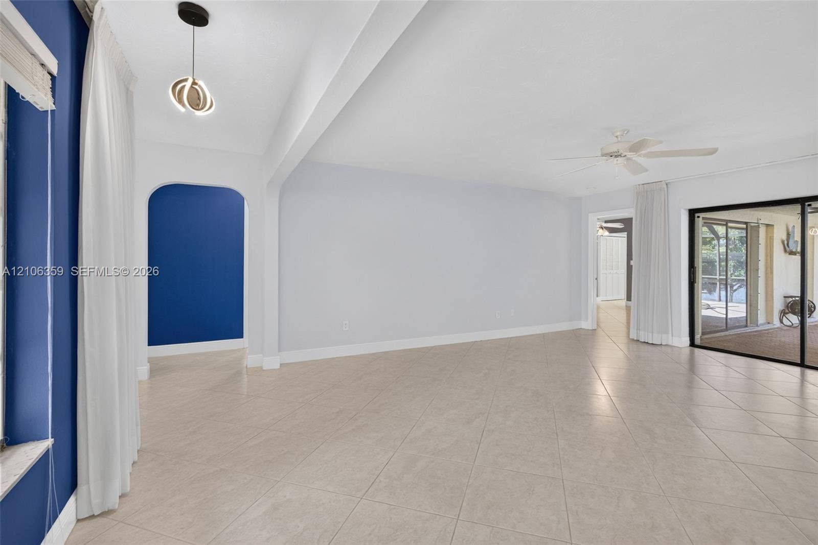 Open interior featuring large-format diagonal tile flooring, an arched entryway, recessed lighting, and sliding glass doors
