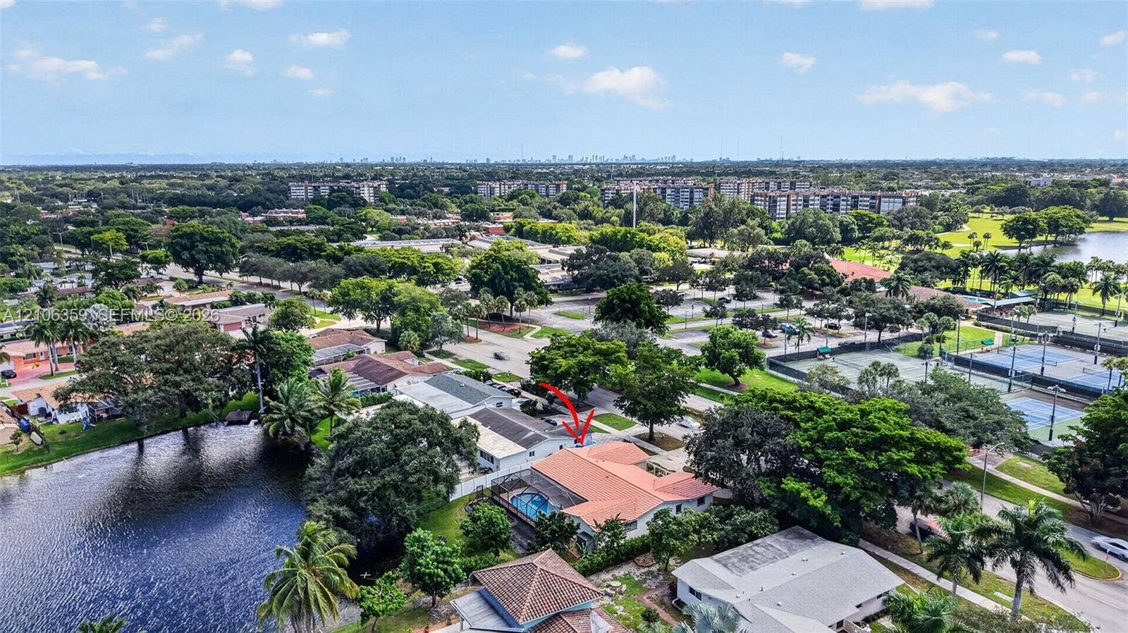 Aerial perspective of a single-story residence featuring a terracotta-style tile roof, an integrated swimming pool, and direct waterfront positioning