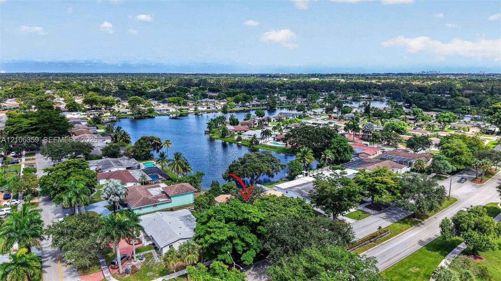 Aerial perspective featuring mature trees, a multi-pitched roofline, and proximity to a large body of water