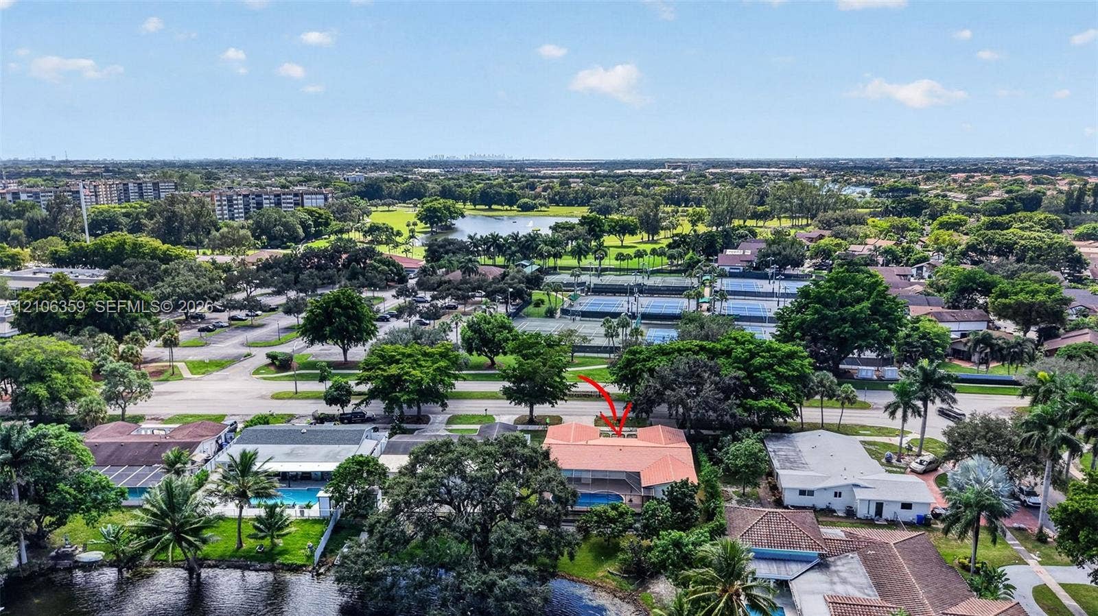 Aerial perspective of property featuring a tile roof, private swimming pool, and lakefront lot with mature landscaping