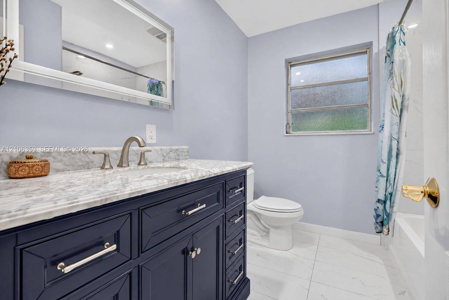 Bathroom featuring a designer vanity with polished stone countertop, undermount sink, brushed-nickel faucet, and large-format tile flooring