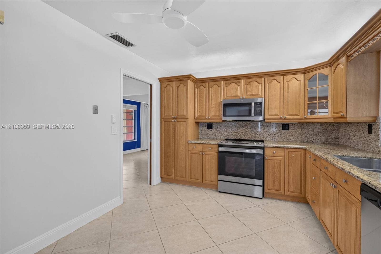 Kitchen featuring wood cabinetry, stone-finish countertops, stainless steel appliance suite, and diagonal-set tile flooring