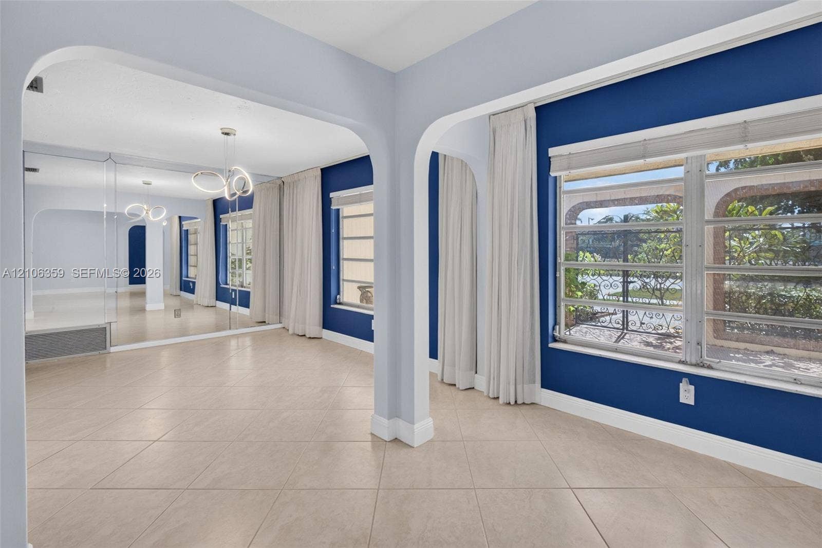 Arched room dividers, large-format tile flooring, mirrored wall paneling, modern multi-ring pendant lighting, and multi-pane horizontal windows