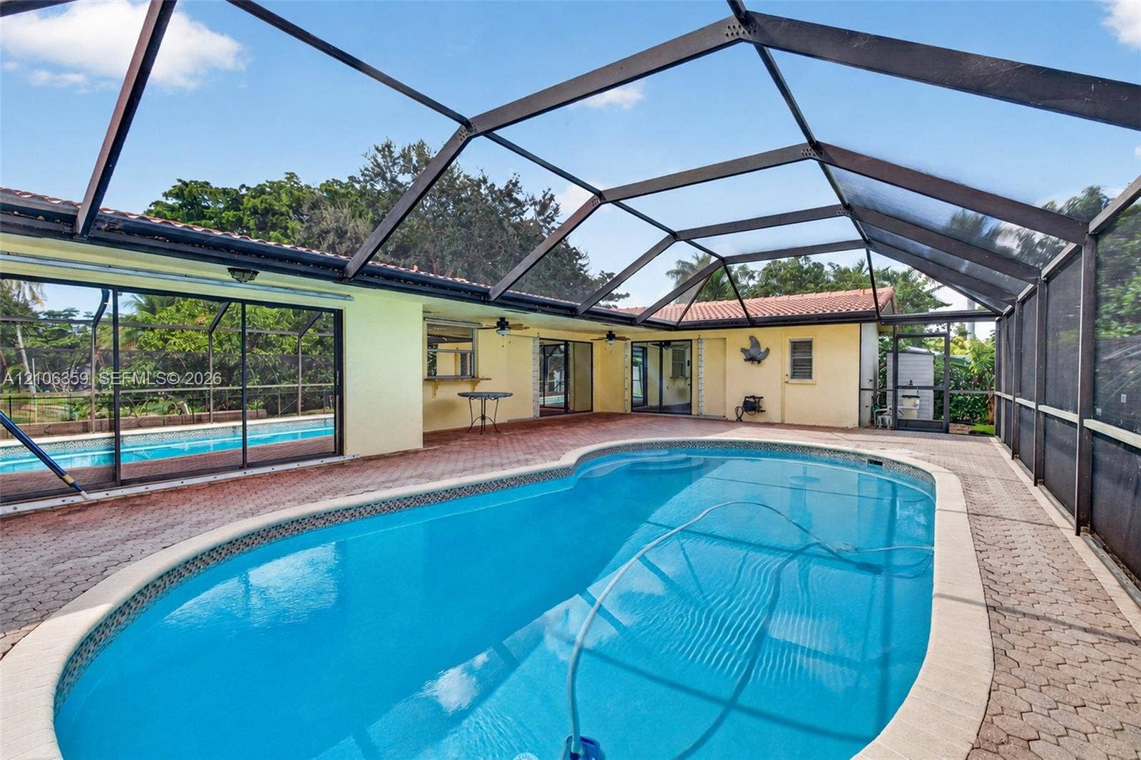 Screen-enclosed patio featuring a paver deck, a kidney-shaped in-ground pool, and built-in wall-mounted ceiling fans