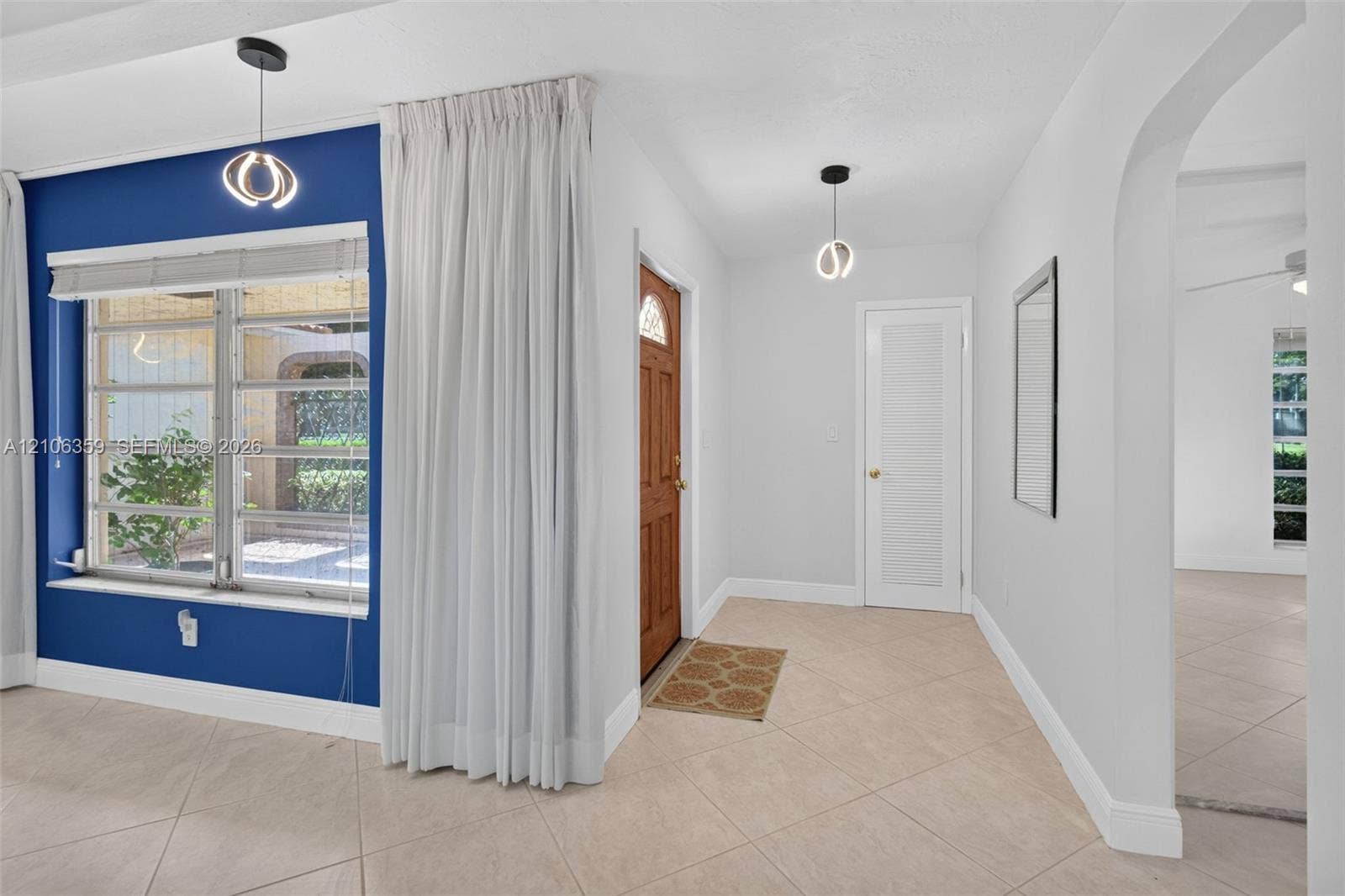 Entryway featuring tile flooring, a solid wood entry door with glass inlay, dual modern geometric pendant light fixtures, and an arched entryway