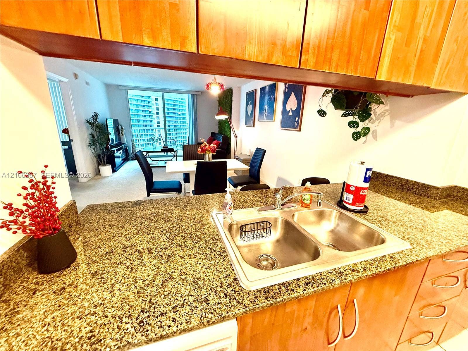 Kitchen featuring stone countertops, dual-basin stainless steel sink, and wood-finish cabinetry