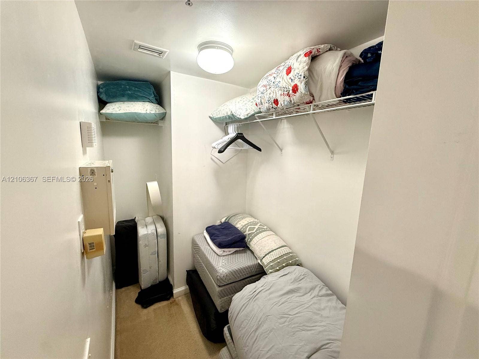 Storage space featuring built-in wire shelving and a ceiling-mounted light fixture