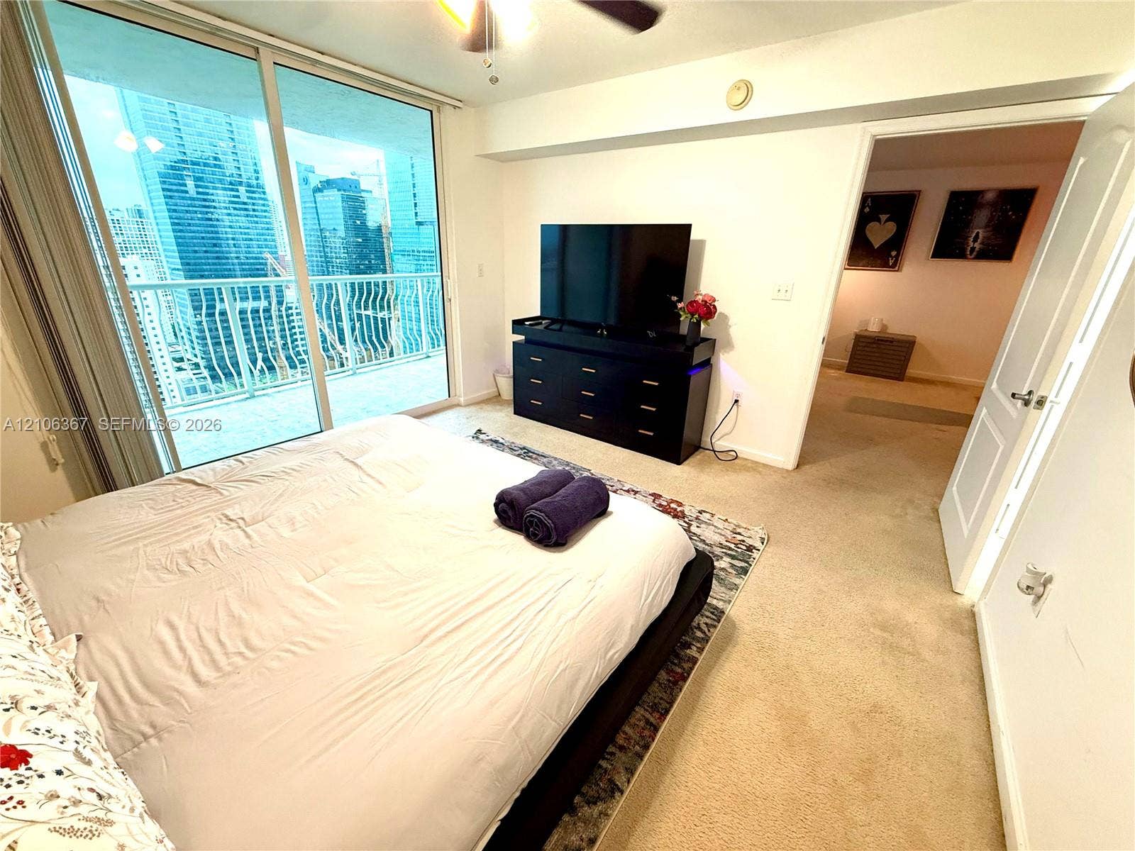 Full-height glass sliding doors leading to a private balcony with metal railings and neutral carpeting