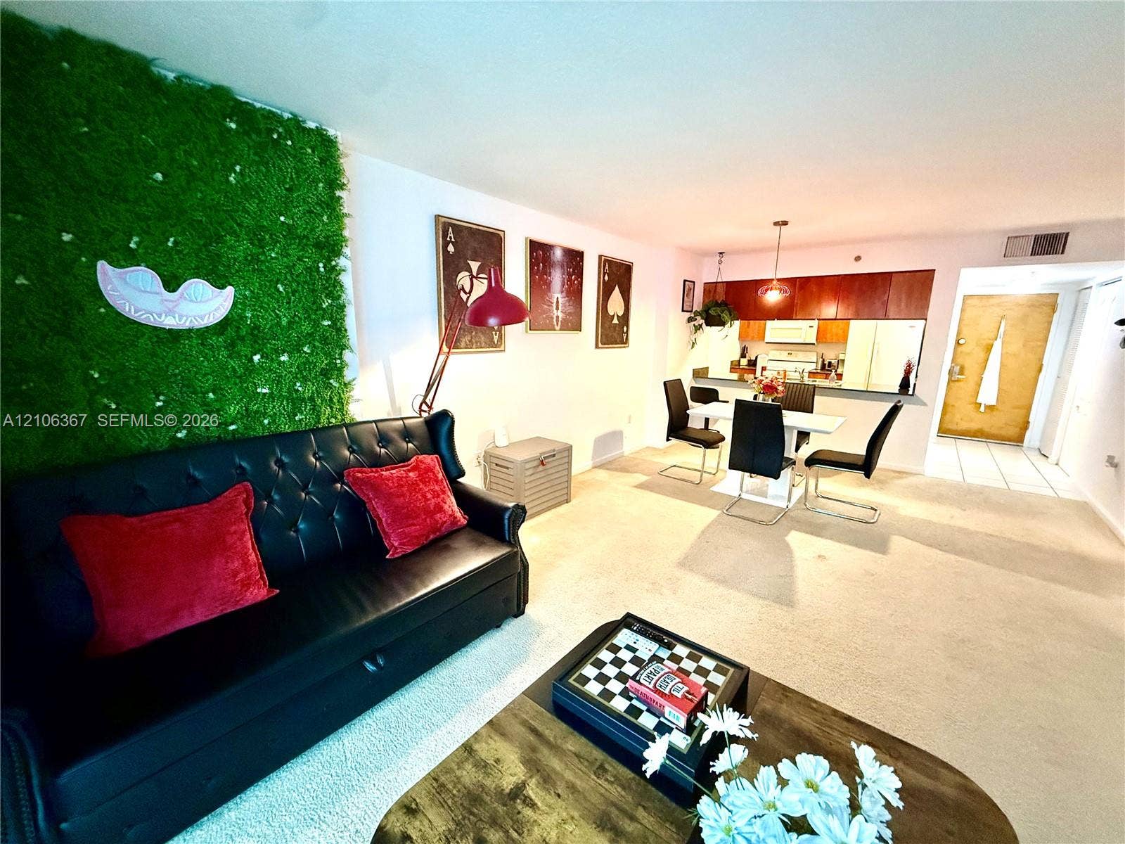 Open-concept interior featuring a decorative wall accent, kitchen with wood-finish cabinetry, and neutral carpeting