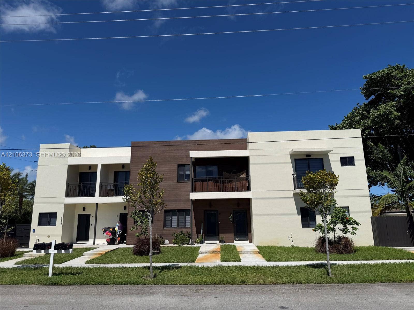 5927 Buchanan Street, Hollywood, FL 33021 Contemporary two-story exterior featuring multi-textured facade, wood-finish paneling, private balconies with metal railings, and concrete walkways