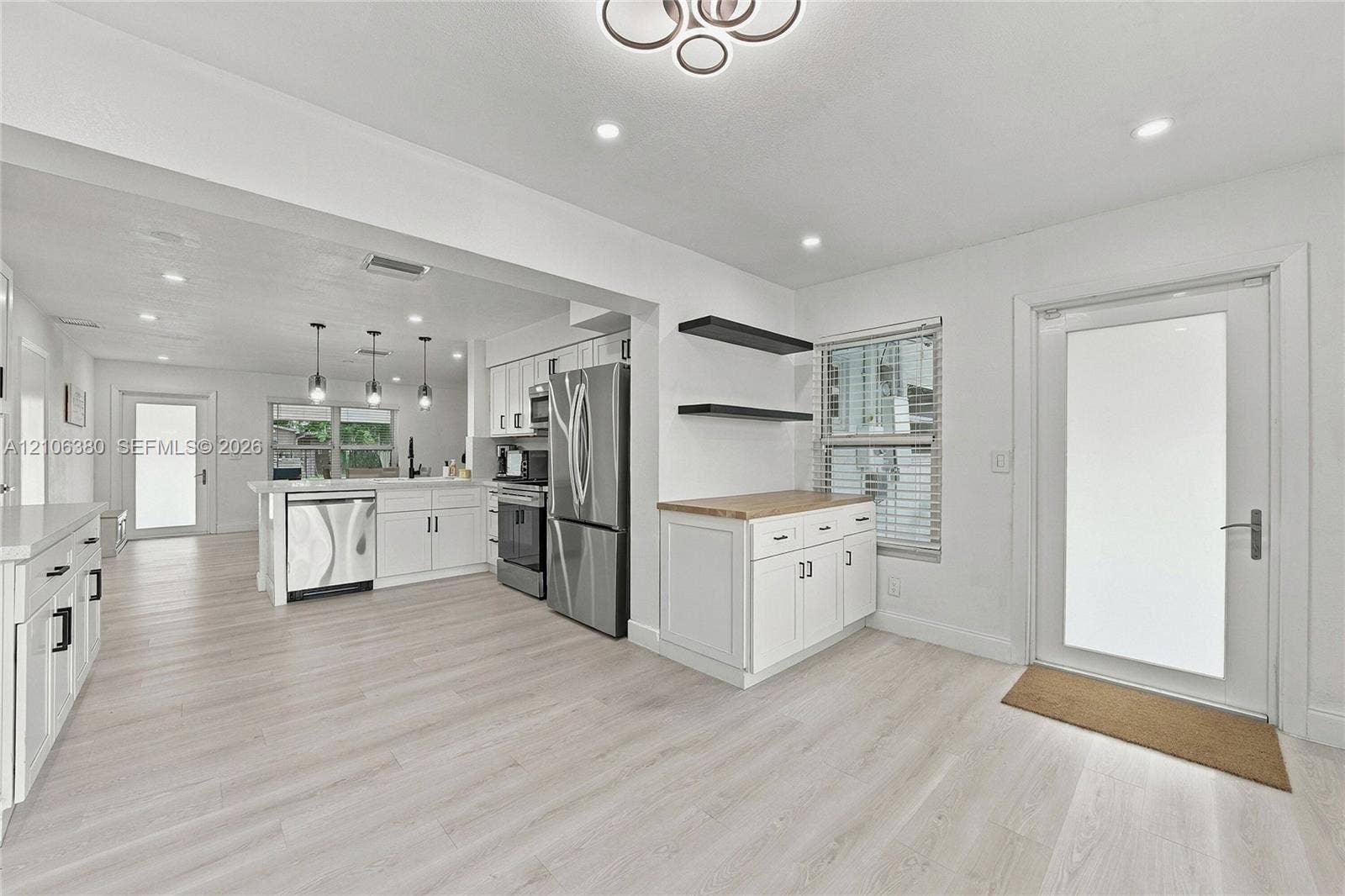 Kitchen featuring white cabinetry, stainless steel appliances, wood-finish flooring, recessed lighting, and a butcher-block countertop workspace with floating shelving