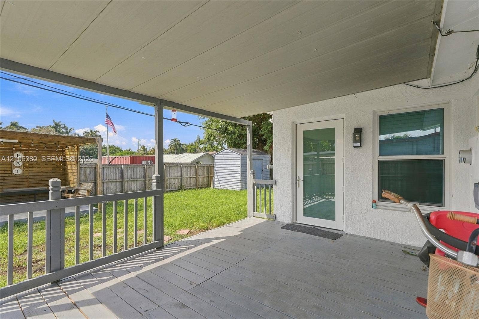 Covered wood-deck porch featuring a railing, full-glass exterior door, and stucco wall finish