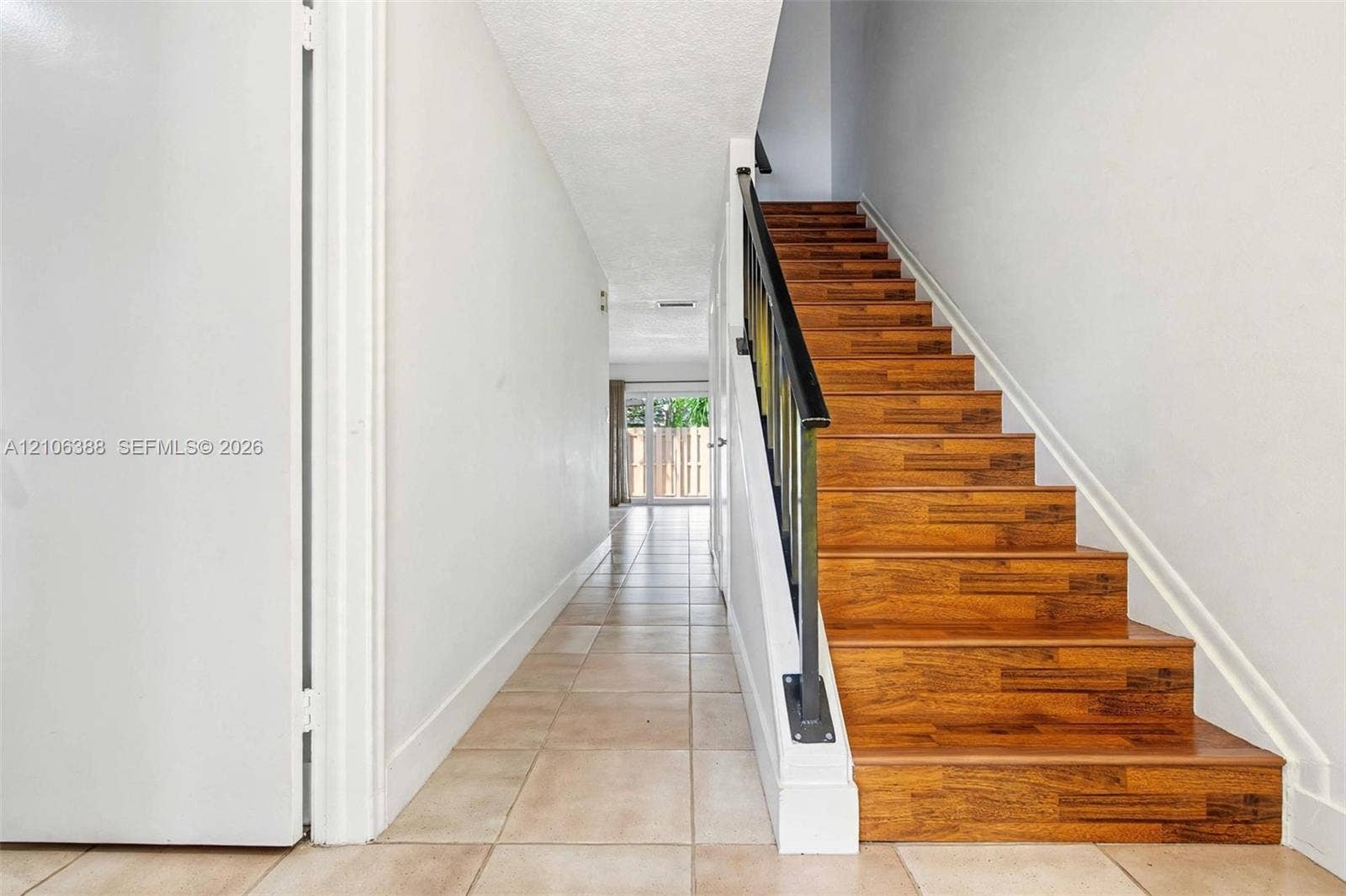 8110 SW 82nd Court, Miami, FL 33143 Entryway featuring square ceramic floor tiling, staircase with wood-finish treads, and a matte black metal handrail